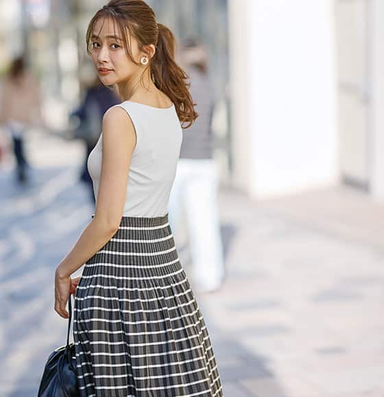 ブラトップボートネックノースリーブを着た女性の画像。きちんと感漂うボートネックは ボレロと合わせても。夏のきれいめ洗練スタイルに。